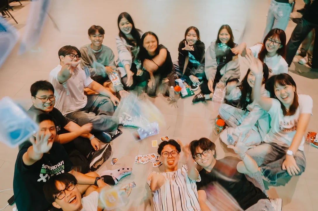 Young people sitting together on the floor, playing card games and laughing between sessions.