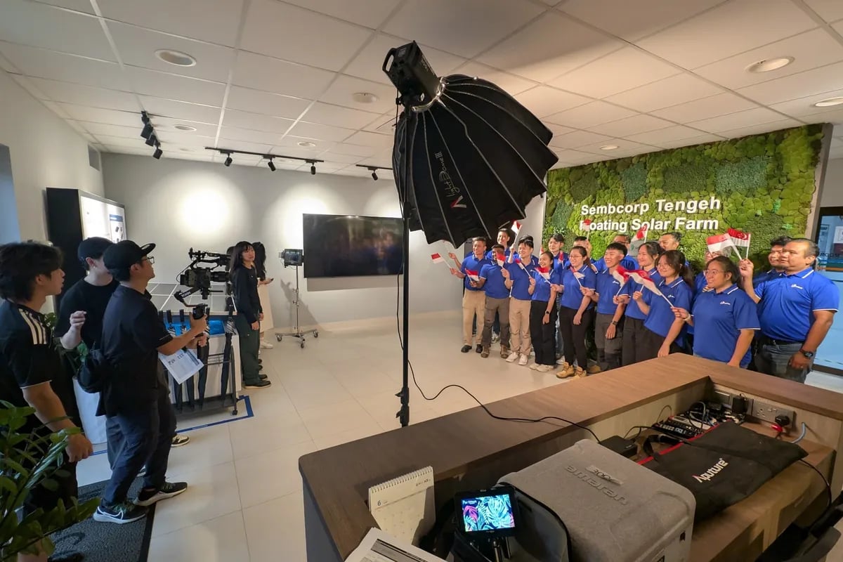 Behind the scenes at the Sembcorp Tengeh Floating Solar Farm — crew with a softbox light filming the team in blue.